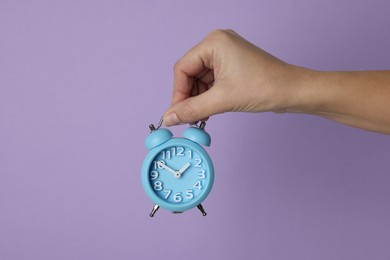 Photo of Woman with alarm clock on lilac background, closeup