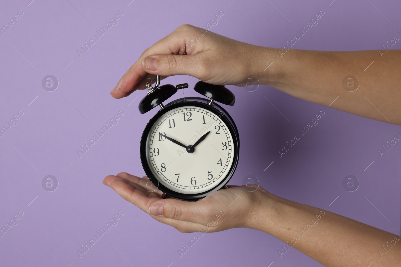 Photo of Woman with alarm clock on lilac background, closeup