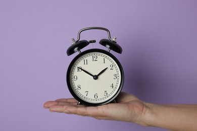 Photo of Woman with alarm clock on lilac background, closeup