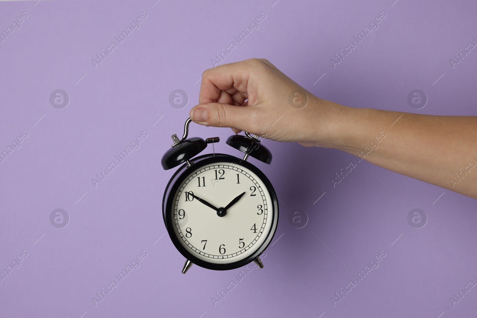 Photo of Woman with alarm clock on lilac background, closeup