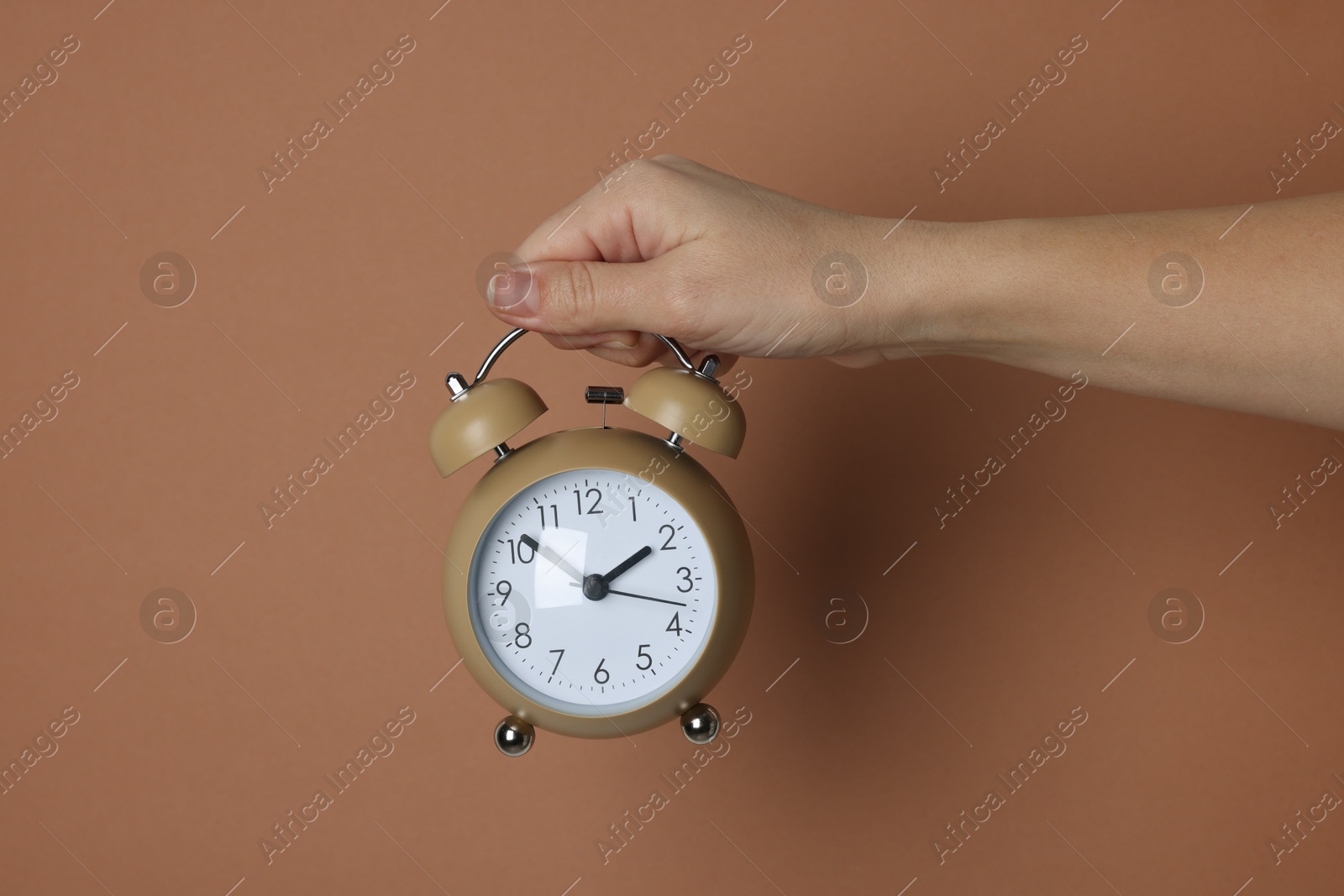 Photo of Woman with alarm clock on brown background, closeup