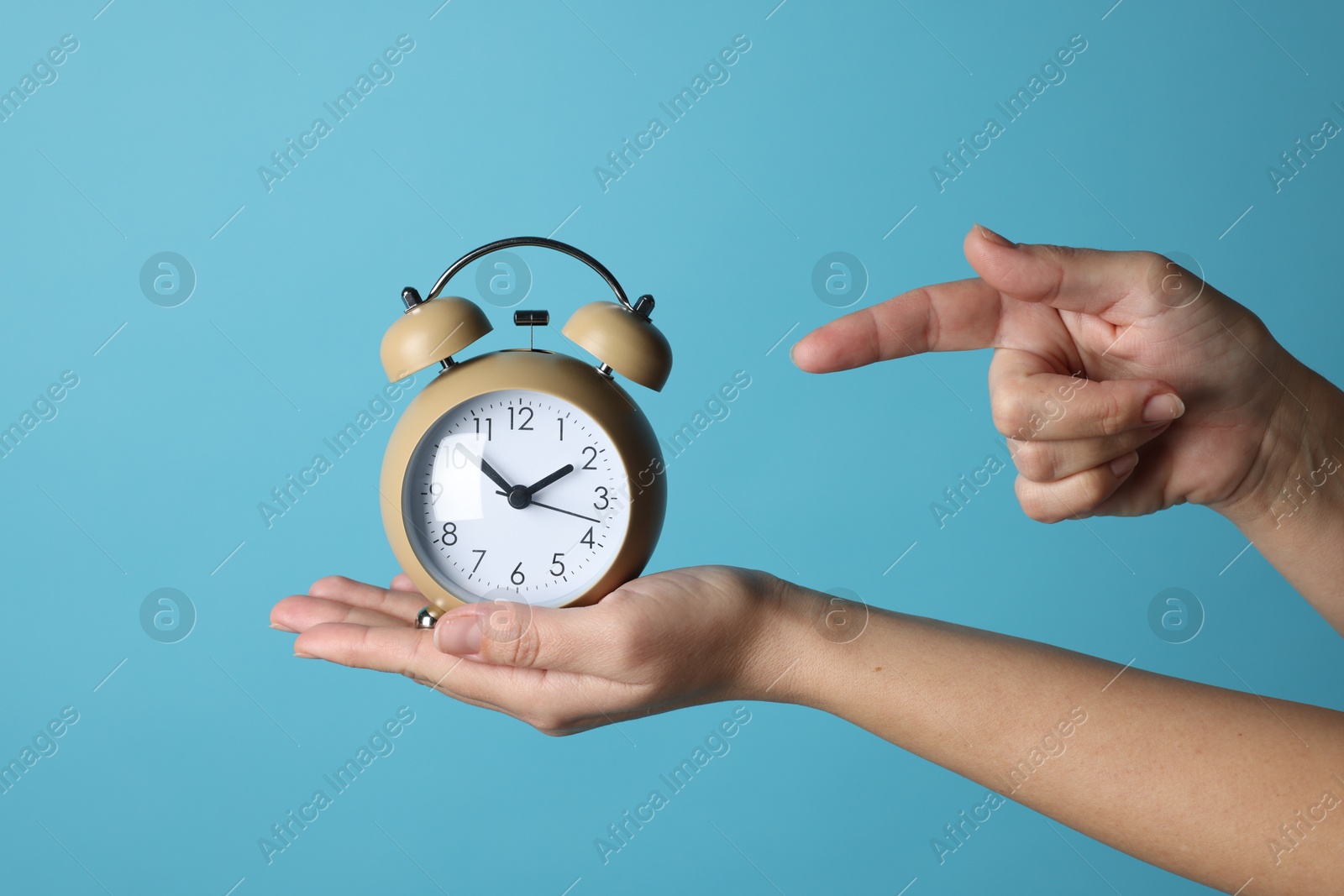 Photo of Woman with alarm clock on blue background, closeup