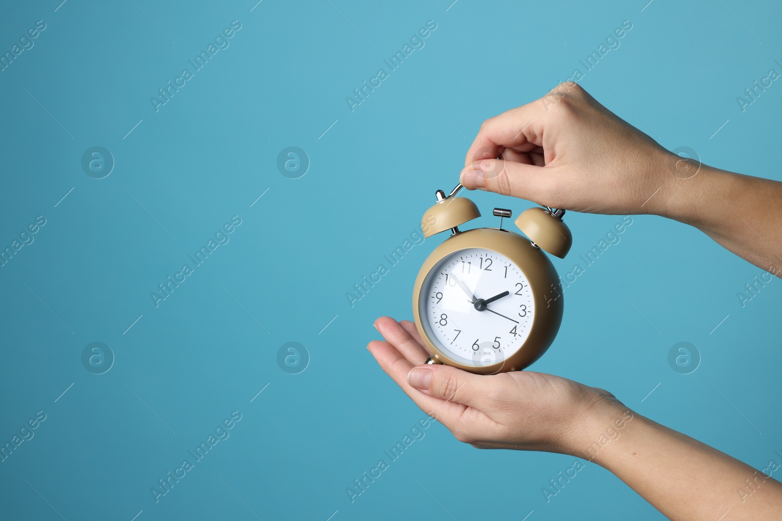 Photo of Woman with alarm clock on blue background, closeup. Space for text