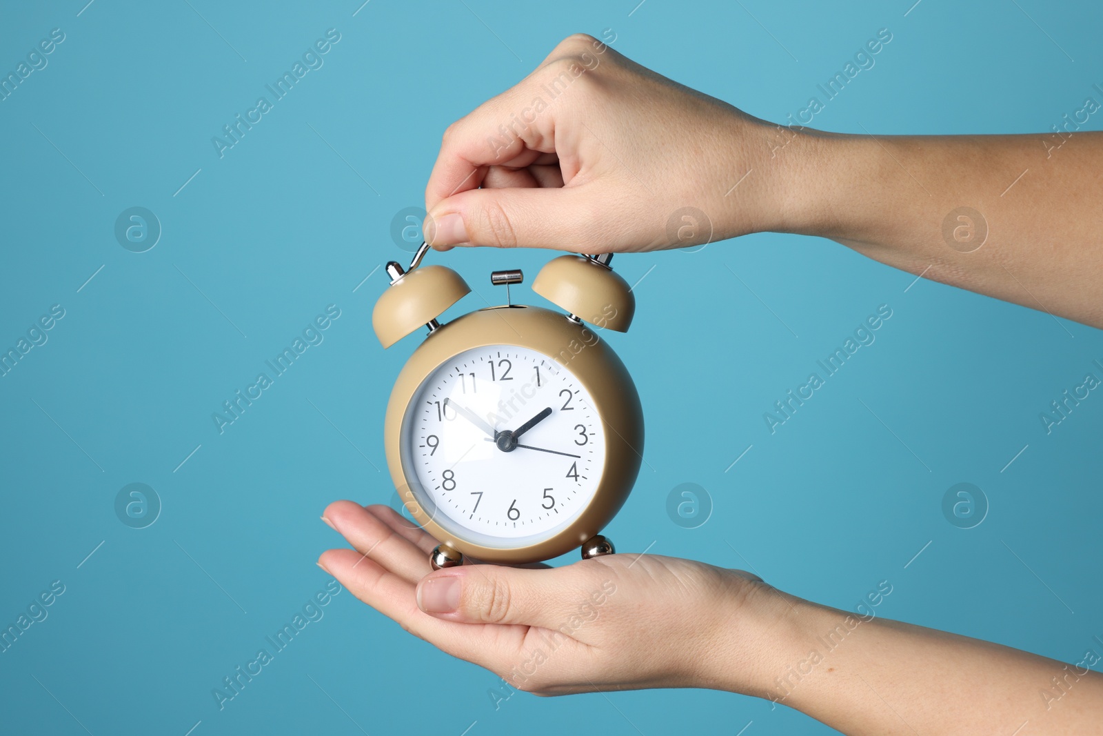 Photo of Woman with alarm clock on blue background, closeup