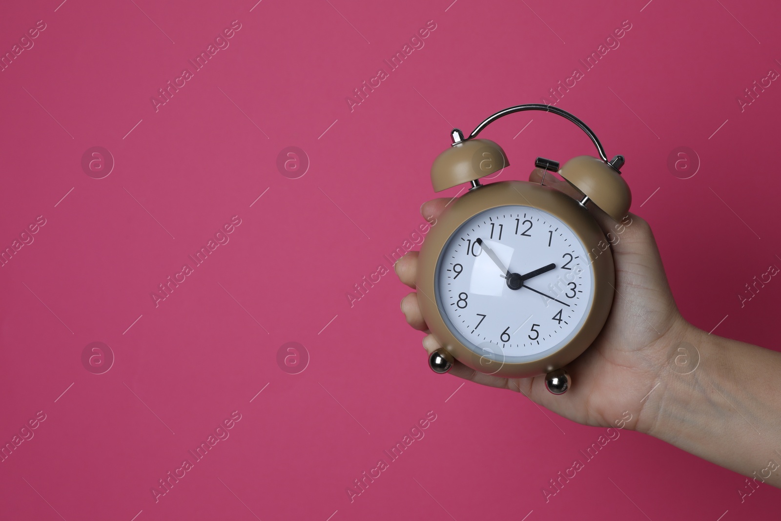 Photo of Woman with alarm clock on crimson background, closeup. Space for text