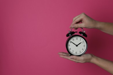 Woman with alarm clock on crimson background, closeup. Space for text