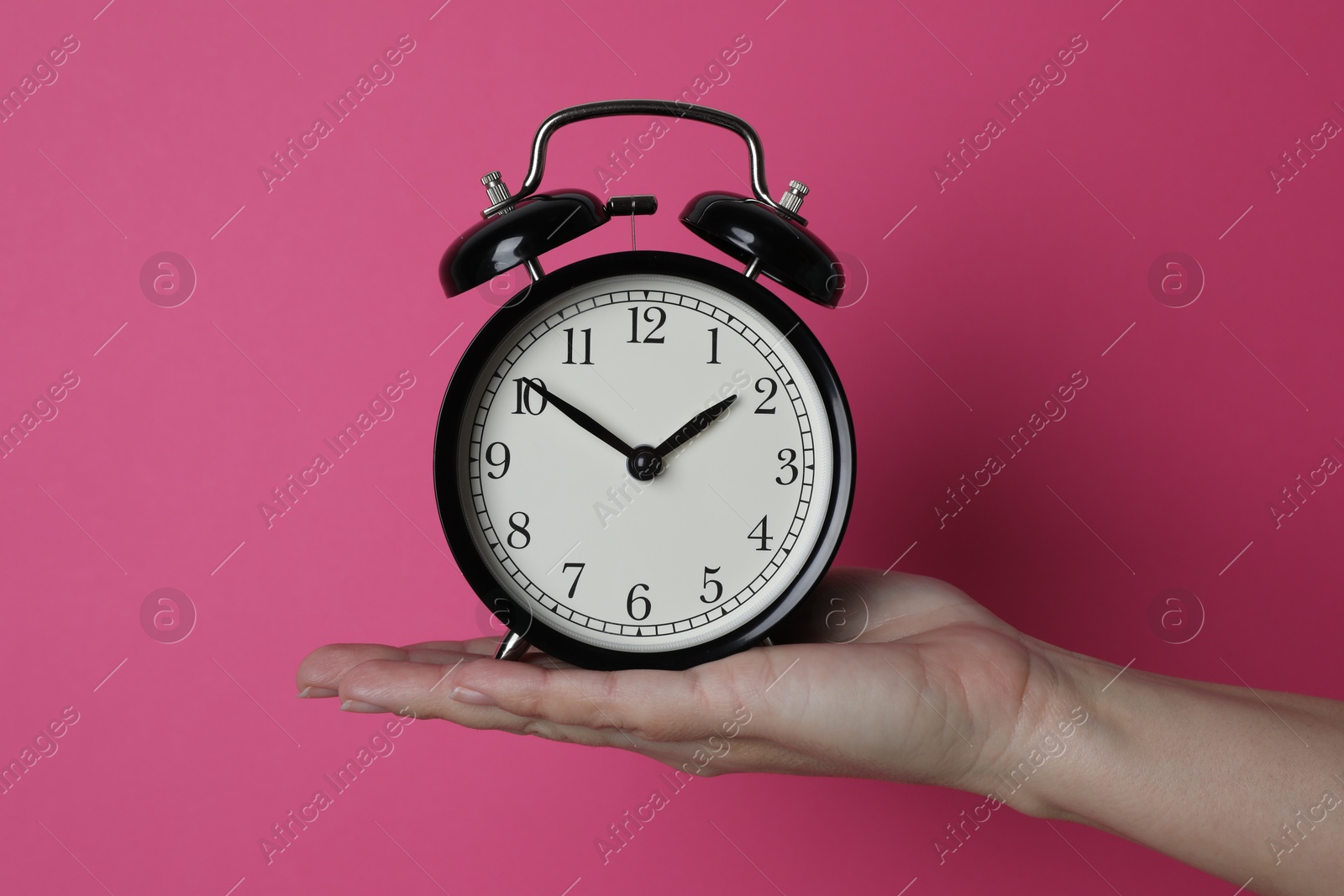 Photo of Woman with alarm clock on crimson background, closeup