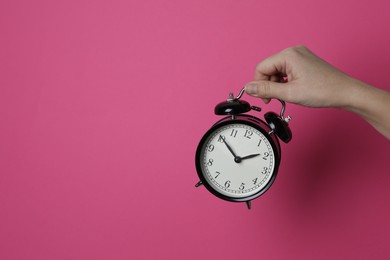 Photo of Woman with alarm clock on crimson background, closeup. Space for text