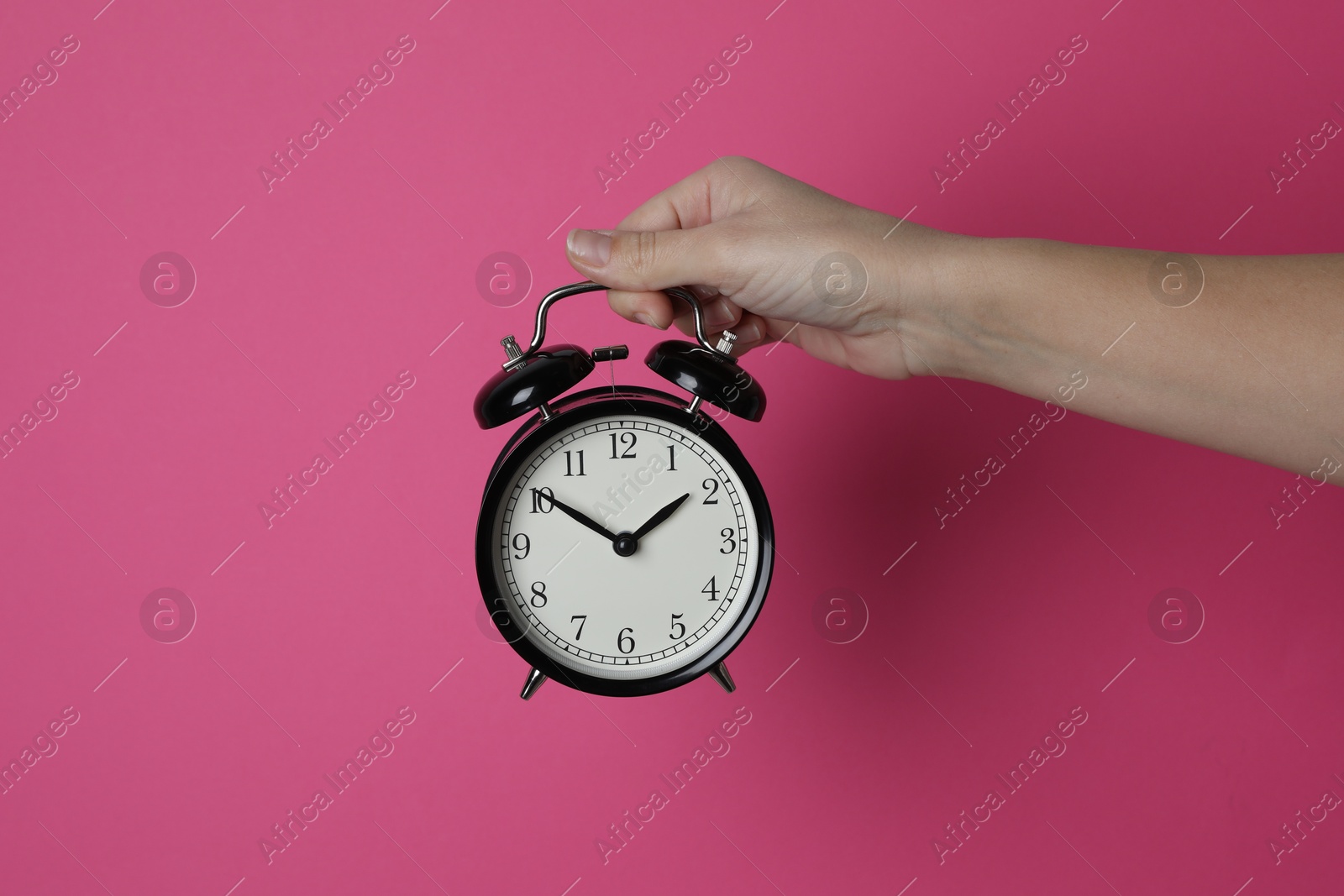 Photo of Woman with alarm clock on crimson background, closeup