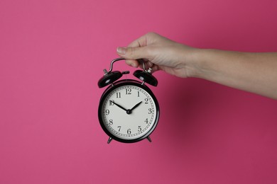 Woman with alarm clock on crimson background, closeup