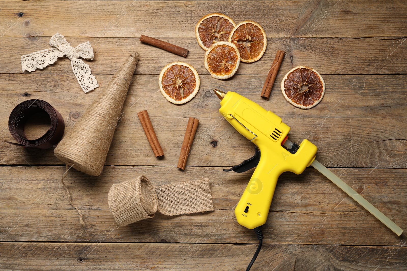 Photo of Hot glue gun and handicraft materials on wooden background, flat lay