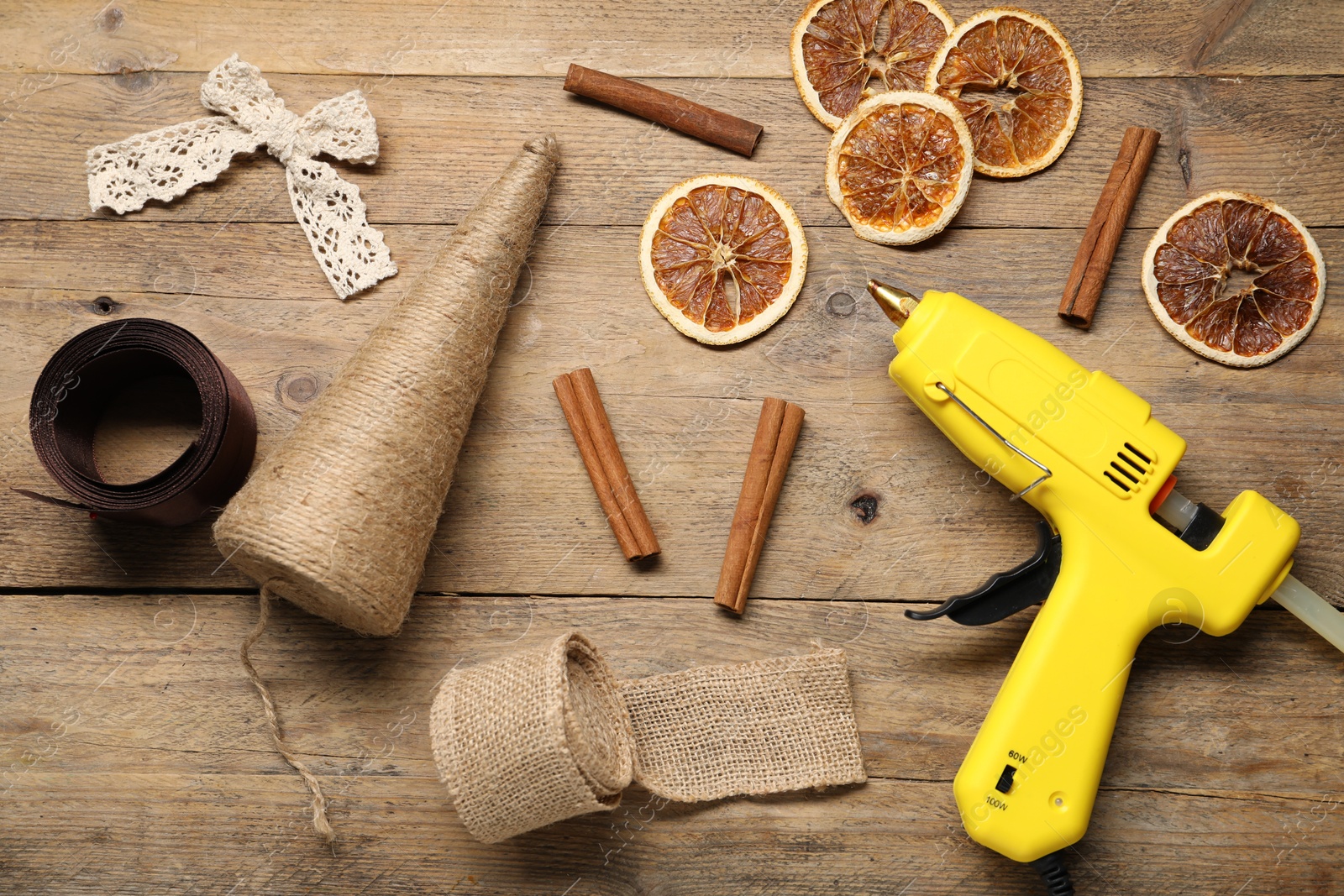 Photo of Hot glue gun and handicraft materials on wooden background, flat lay