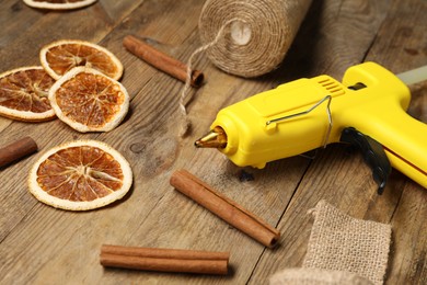 Photo of Hot glue gun and handicraft materials on wooden background, closeup