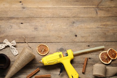 Photo of Hot glue gun and handicraft materials on wooden background, flat lay. Space for text