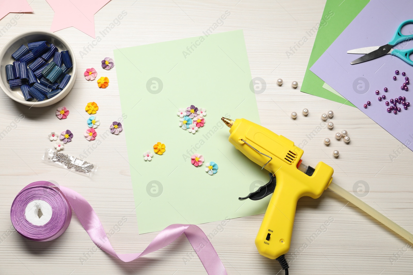 Photo of Hot glue gun and handicraft materials on wooden background, flat lay