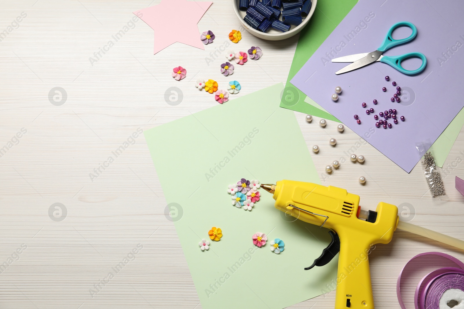 Photo of Hot glue gun and handicraft materials on wooden background, flat lay. Space for text