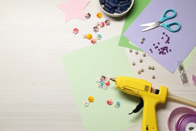 Photo of Hot glue gun and handicraft materials on wooden background, flat lay. Space for text