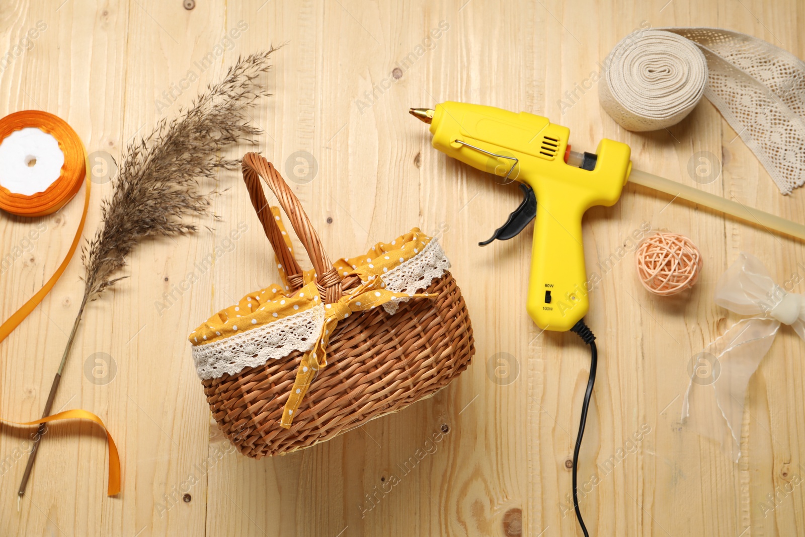 Photo of Hot glue gun and handicraft materials on wooden background, flat lay