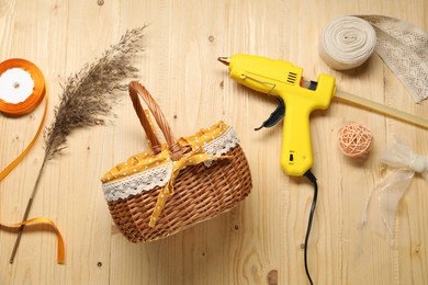 Photo of Hot glue gun and handicraft materials on wooden background, flat lay