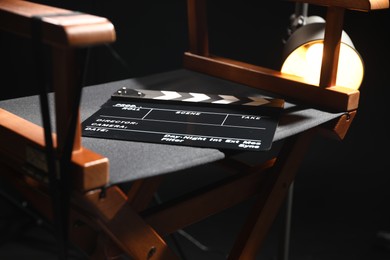 Photo of Director's chair with clapperboard on black background, closeup