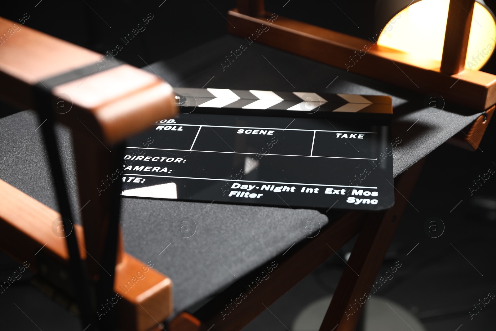 Photo of Director's chair with clapperboard on black background, closeup