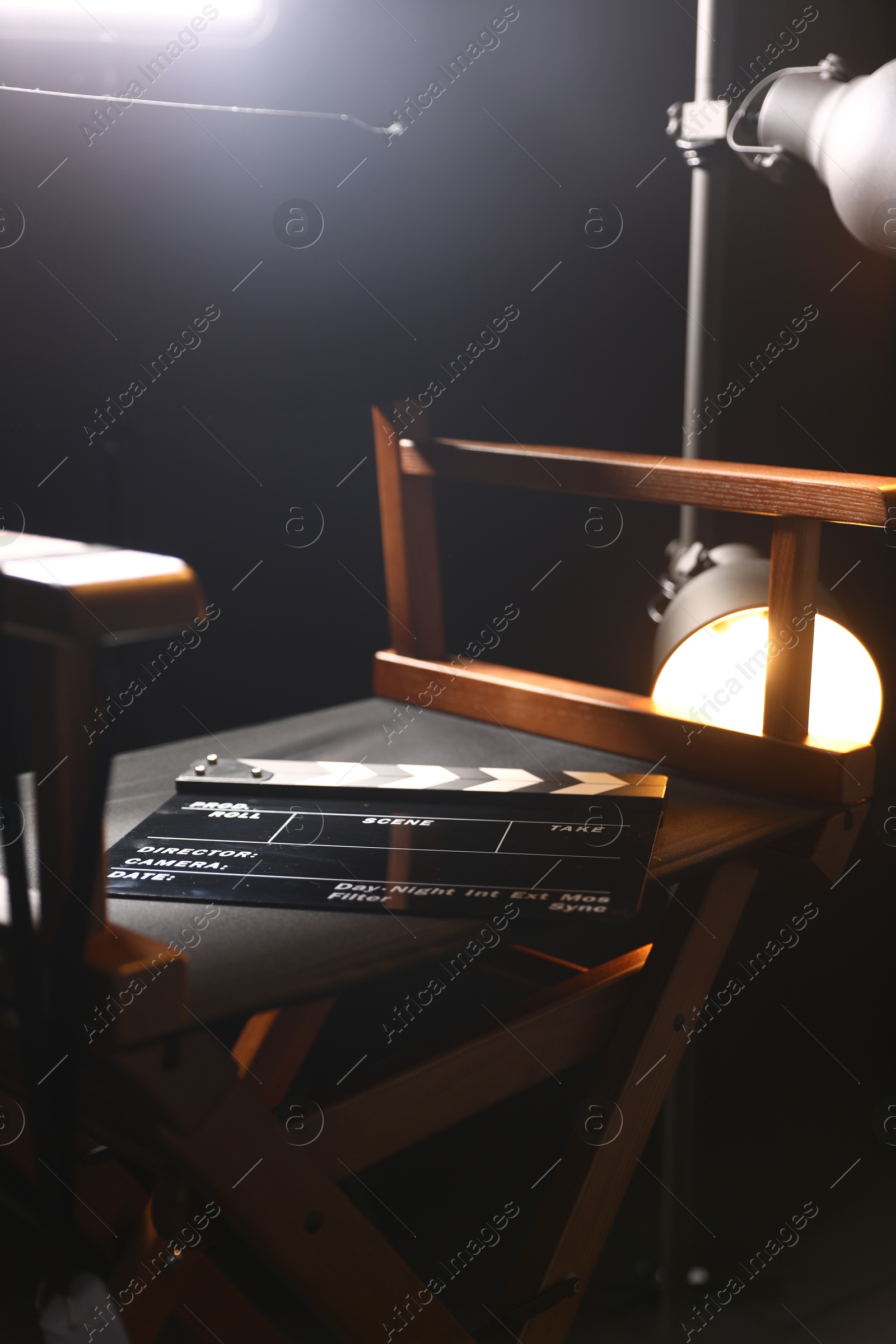 Photo of Director's chair with clapperboard on black background, closeup