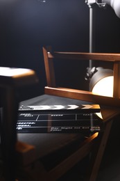 Photo of Director's chair with clapperboard on black background, closeup