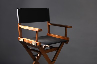 Photo of One empty director's chair on grey background, closeup. Space for text