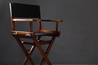 Photo of One empty director's chair on grey background, closeup. Space for text