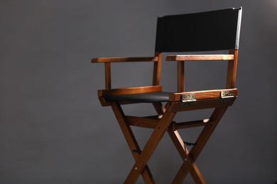 Photo of One empty director's chair on grey background, closeup. Space for text