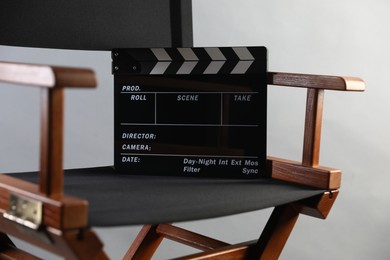 Photo of Director's chair with clapperboard on light grey background, closeup