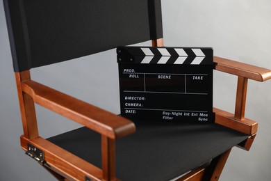 Photo of Director's chair with clapperboard on light grey background, closeup