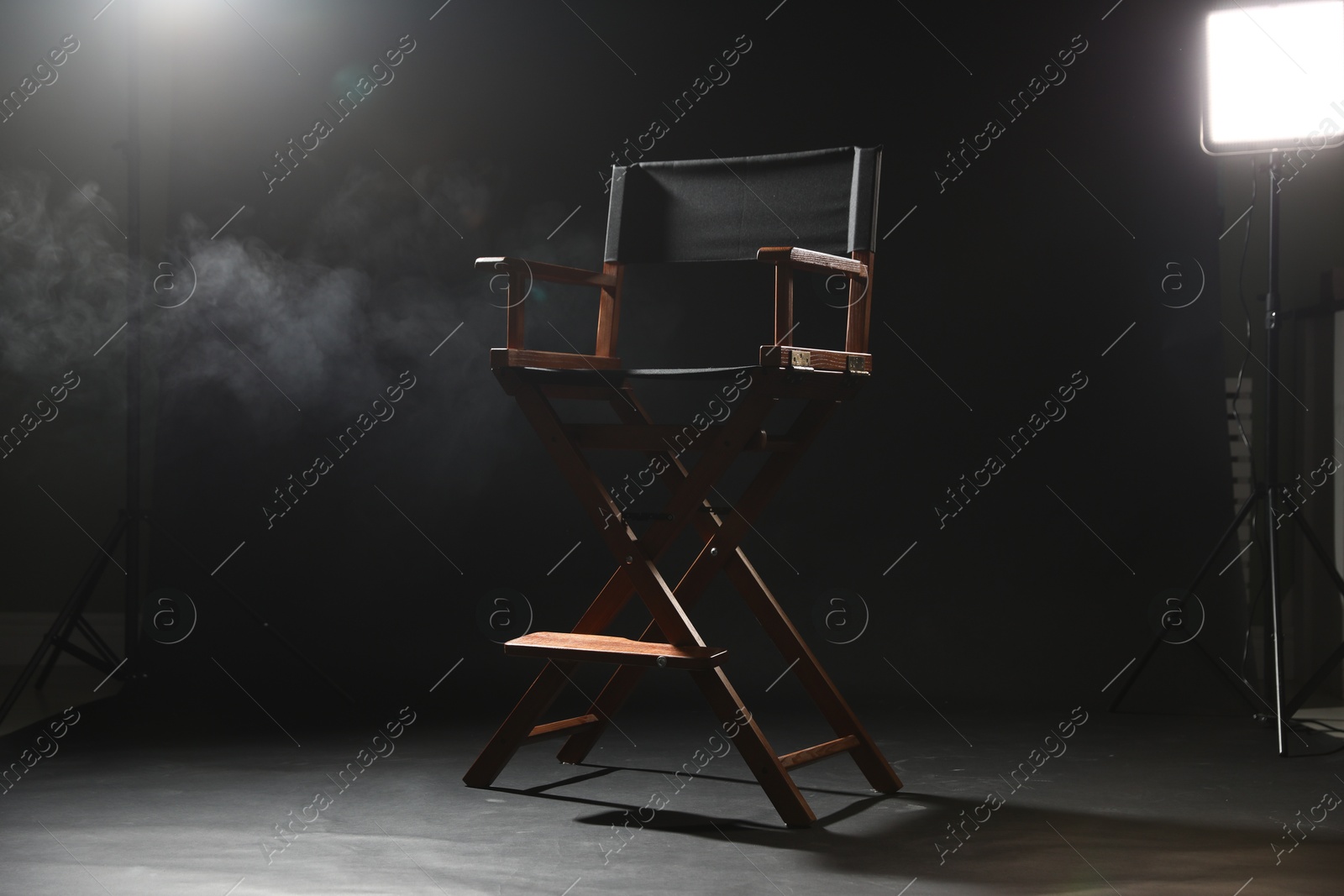 Photo of One empty director's chair on black background with smoke