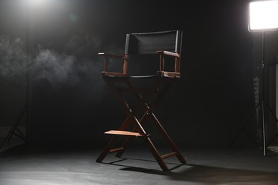 Photo of One empty director's chair on black background with smoke