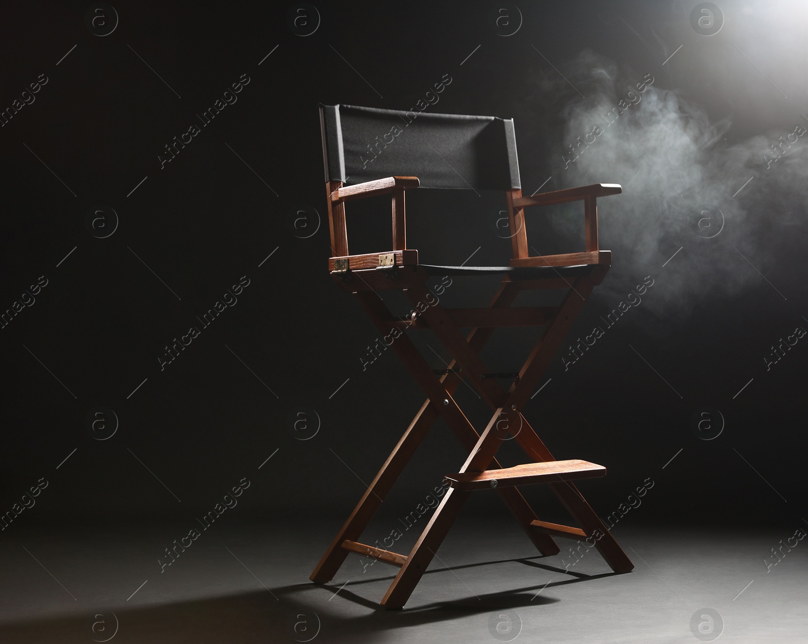 Photo of One empty director's chair on black background with smoke, space for text