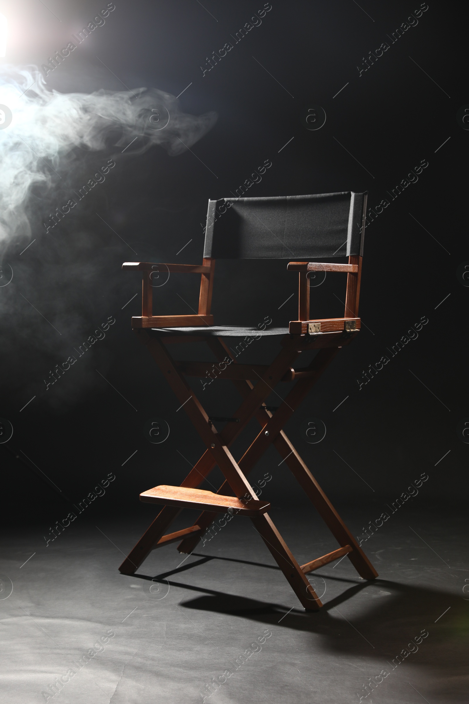 Photo of One empty director's chair on black background with smoke