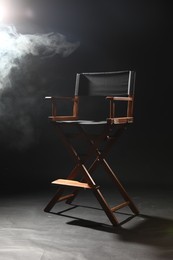 Photo of One empty director's chair on black background with smoke