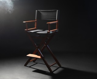 Photo of One empty director's chair on black background with smoke