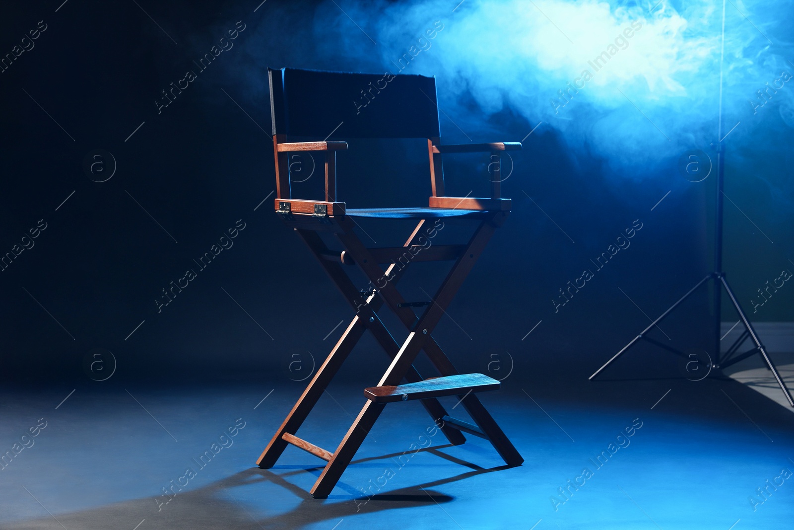 Photo of One empty director's chair on dark blue background with smoke