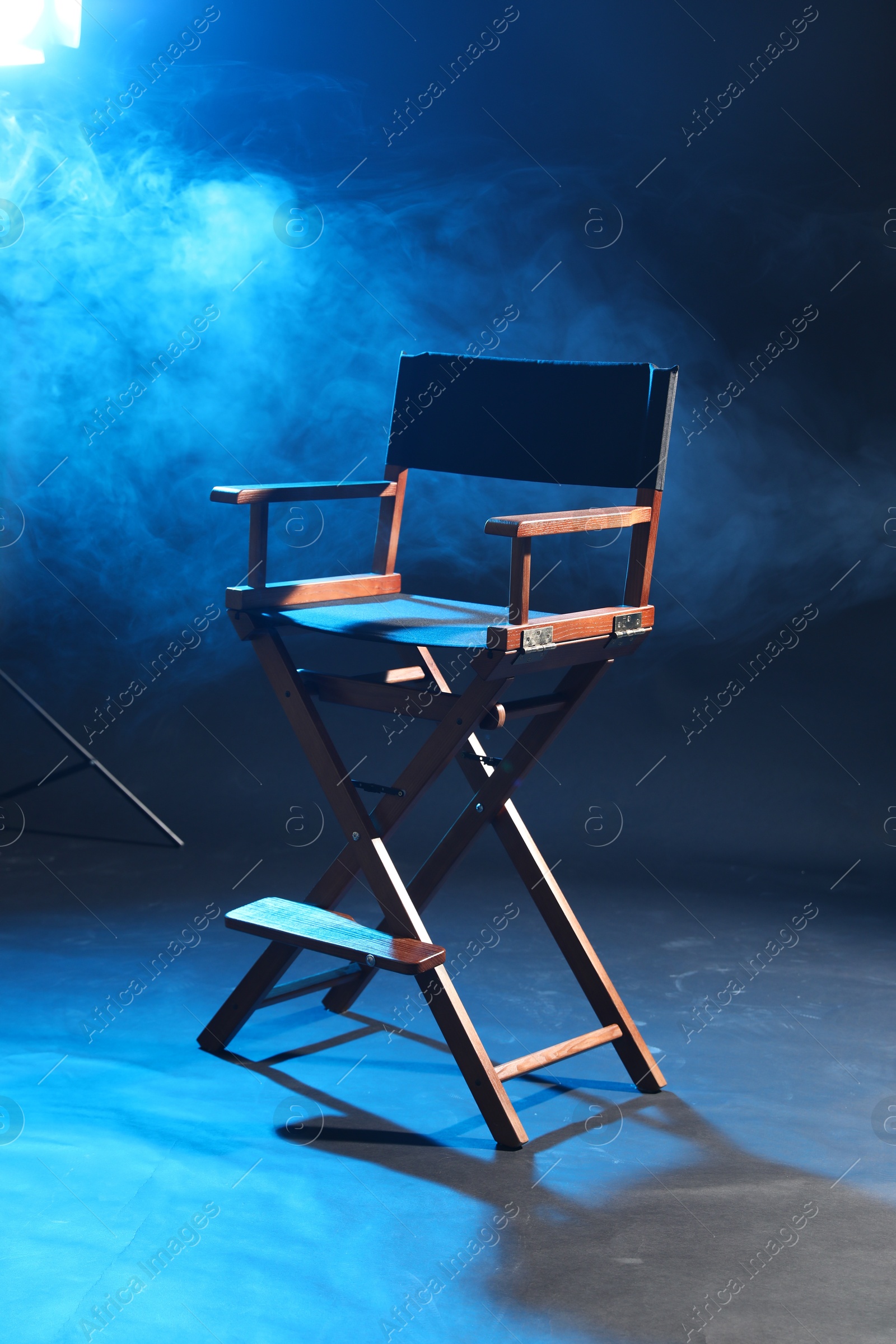 Photo of One empty director's chair on dark blue background with smoke