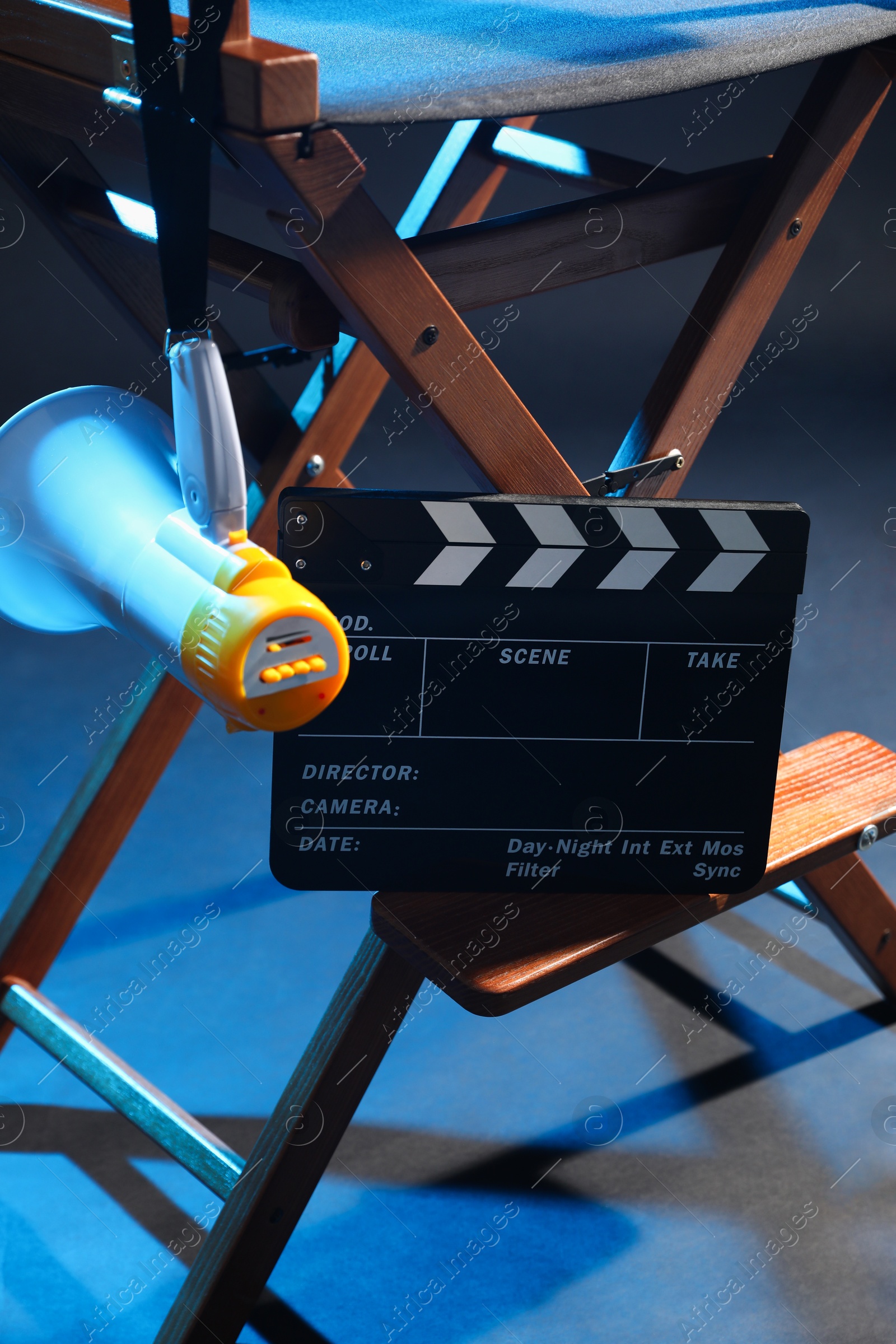 Photo of Director's chair with clapperboard and megaphone on dark background, closeup