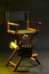 Photo of Director's chair with clapperboard and megaphone on dark background with smoke