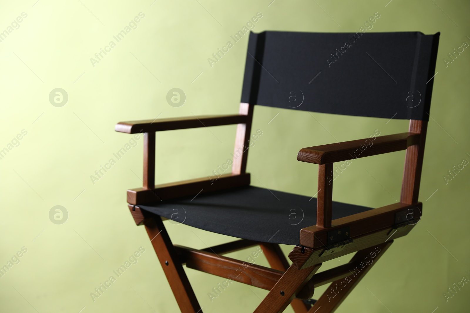 Photo of One empty director's chair on pale olive background, closeup. Space for text