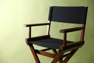 Photo of One empty director's chair on pale olive background, closeup. Space for text