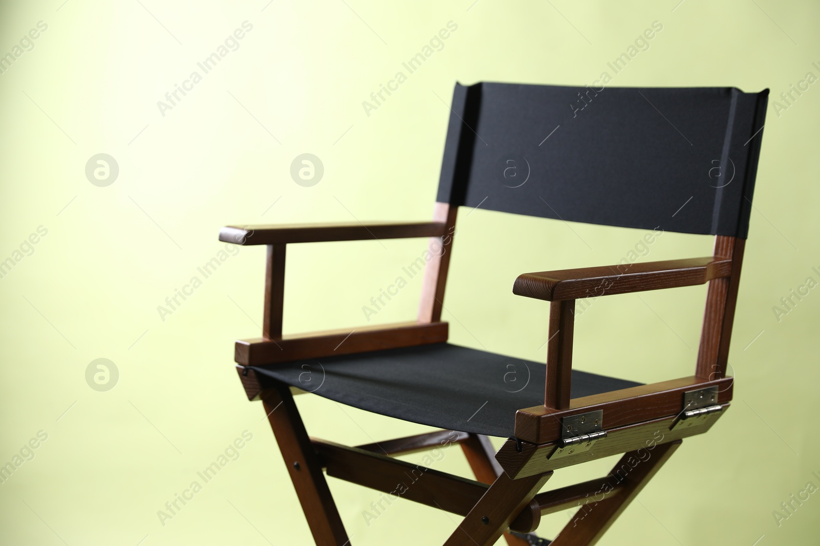 Photo of One empty director's chair on pale olive background, closeup. Space for text