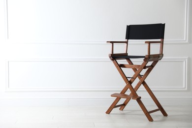 Photo of One empty director's chair near white wall indoors, space for text