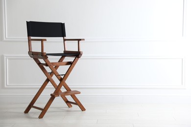 Photo of One empty director's chair near white wall indoors, space for text