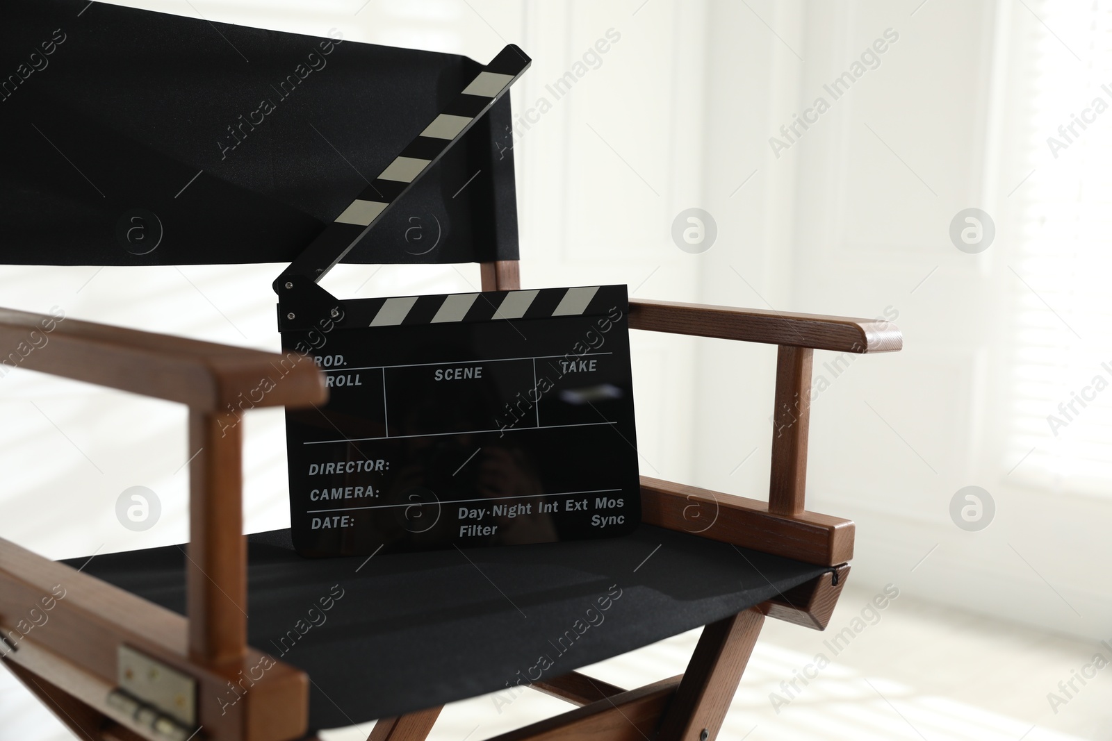 Photo of Director's chair with clapperboard indoors, closeup. Space for text