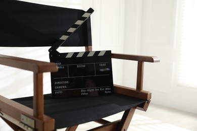 Photo of Director's chair with clapperboard indoors, closeup. Space for text