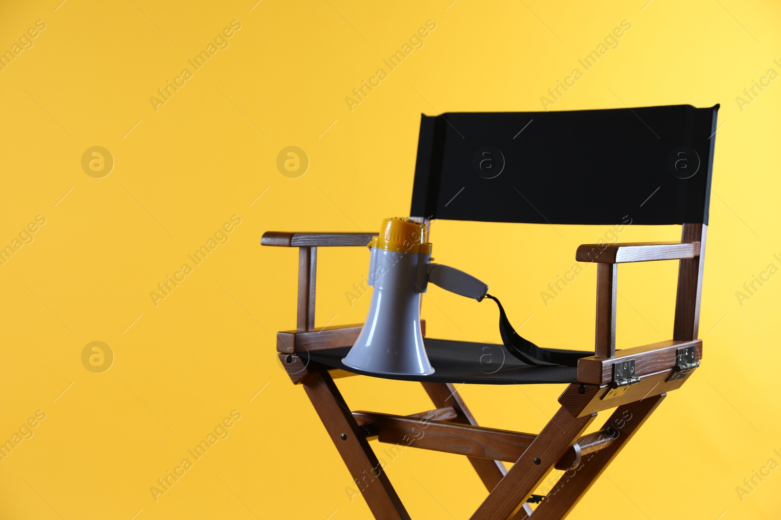 Photo of Director's chair with megaphone on yellow background, space for text